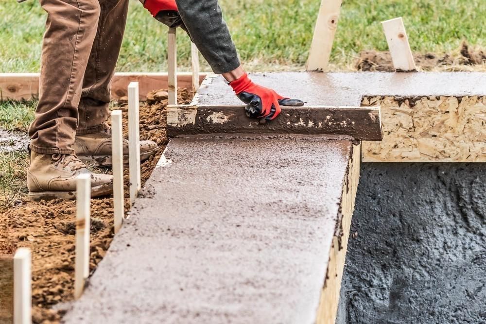 a man is working on a concrete walkway .