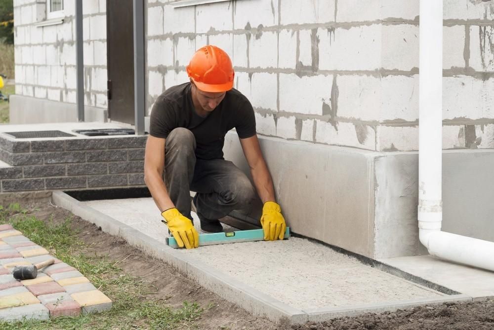 a man is using a level to check the level of a sidewalk .