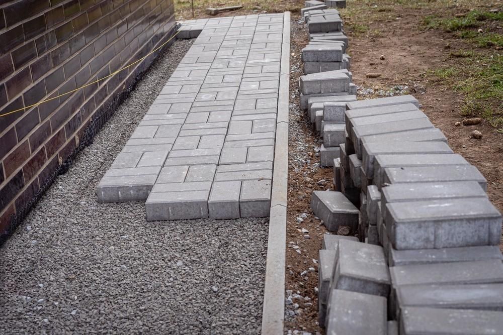 a brick walkway is being built next to a brick wall