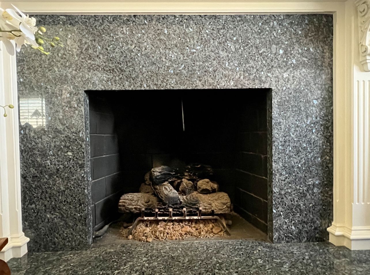 A fireplace in a living room with a black granite surround