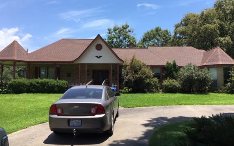 A car is parked in front of a large house.