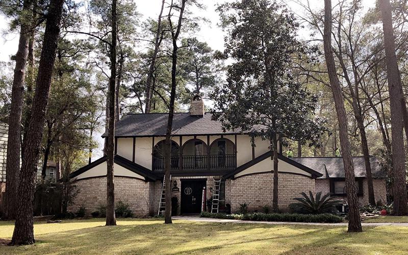 A large house is surrounded by trees on a sunny day.