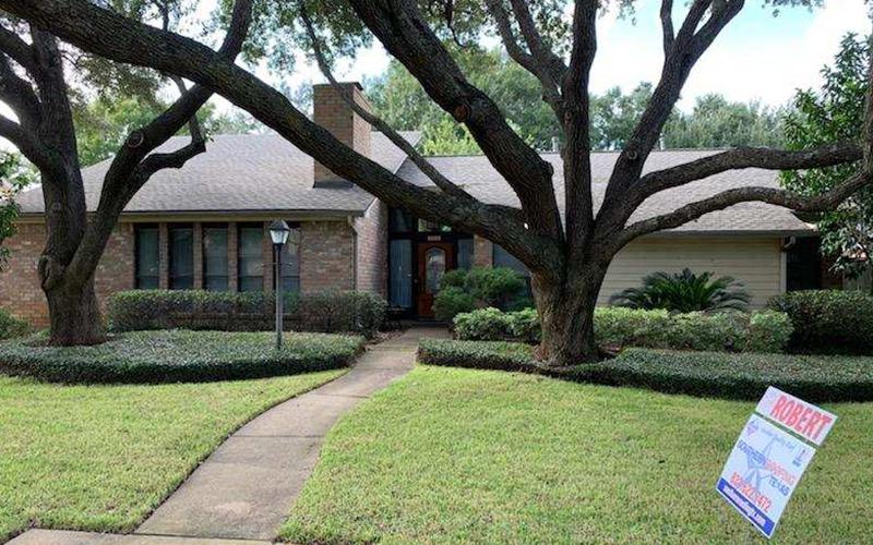 A house with a for sale sign in front of it.