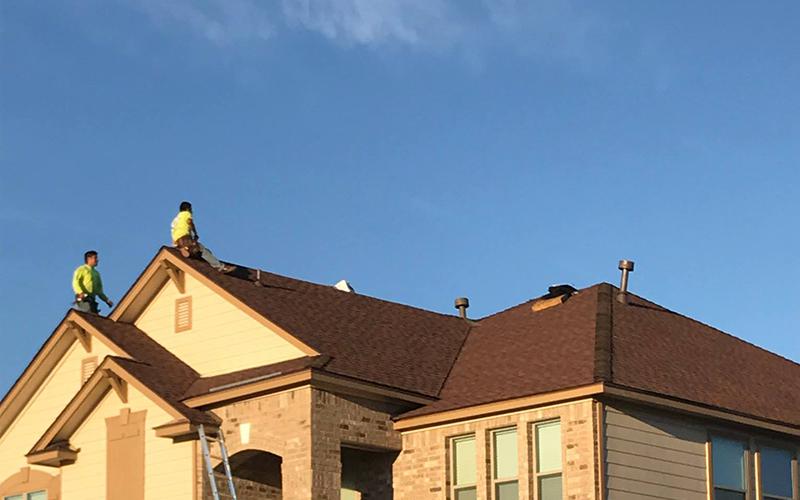 Two men are working on the roof of a house.