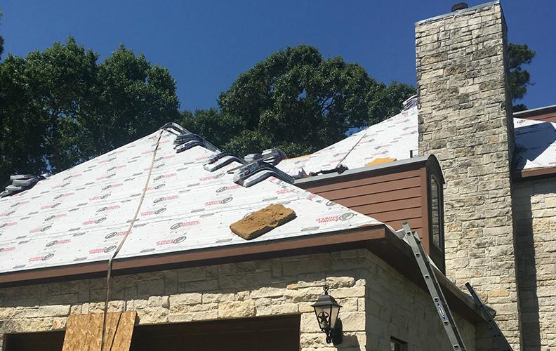 A roof is being installed on a brick house.