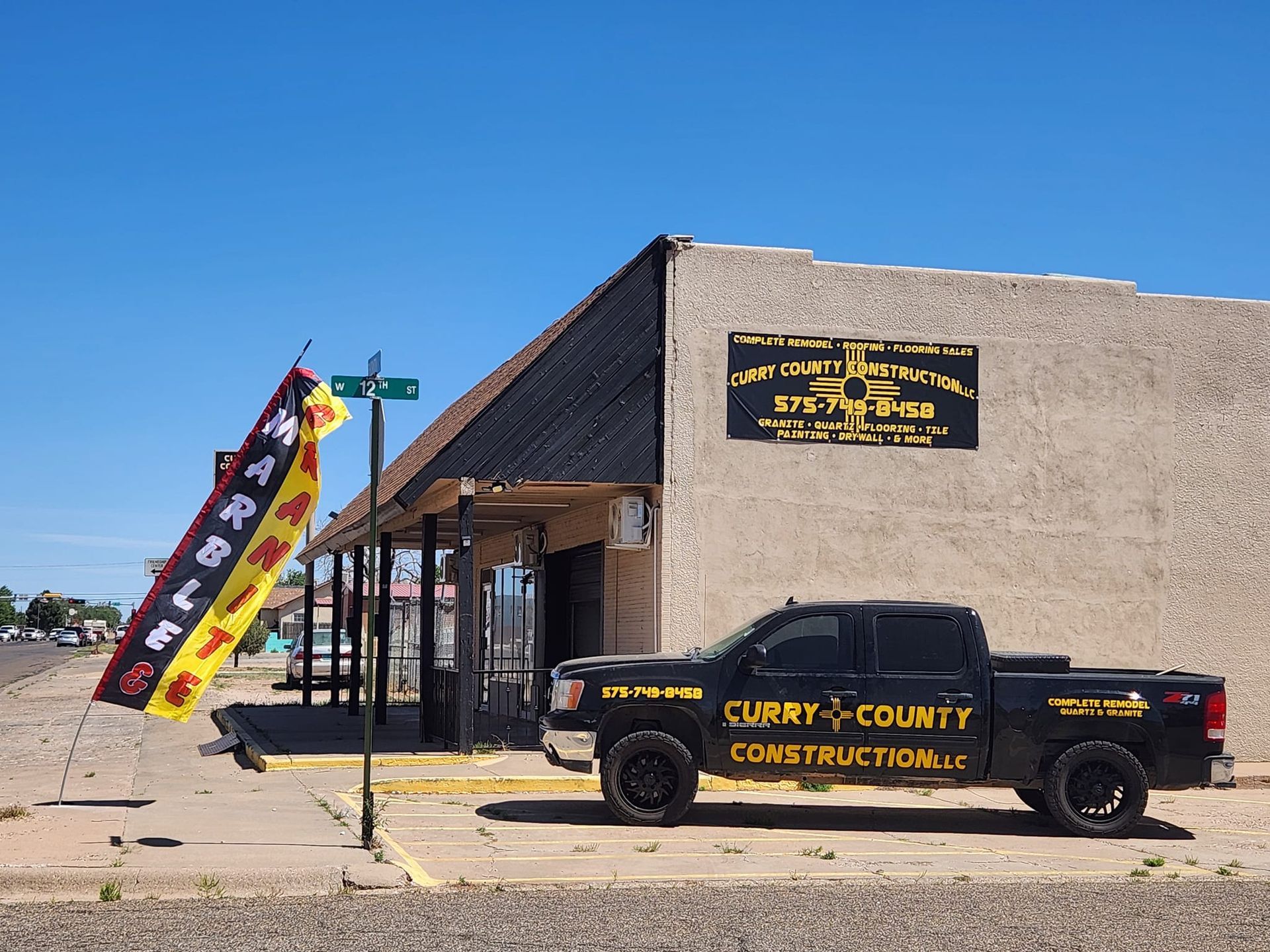 A curry county construction truck is parked in front of a building