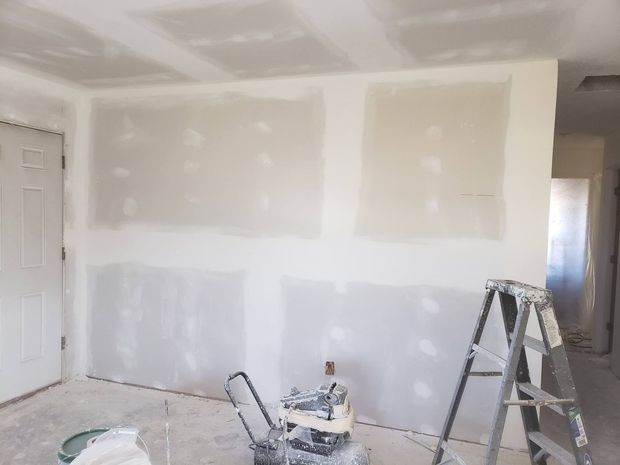A room is being painted with a ladder and a vacuum cleaner.