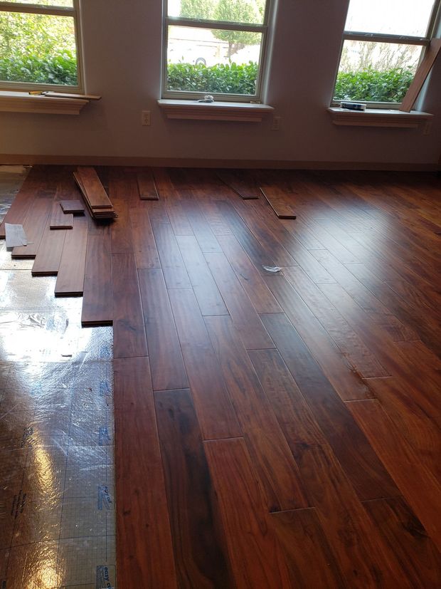 A room with a wooden floor and three windows.