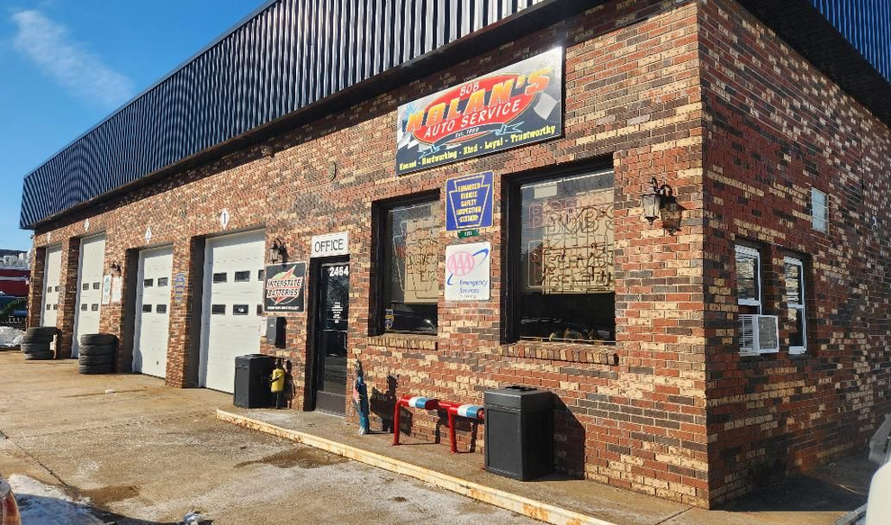 Brick auto repair shop with garage doors, windows, and a sign that says 