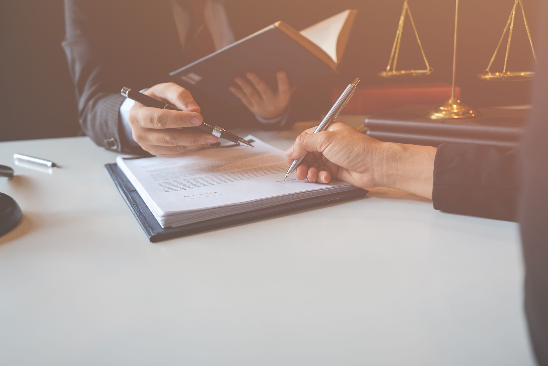 A man and a woman are sitting at a table signing a document.