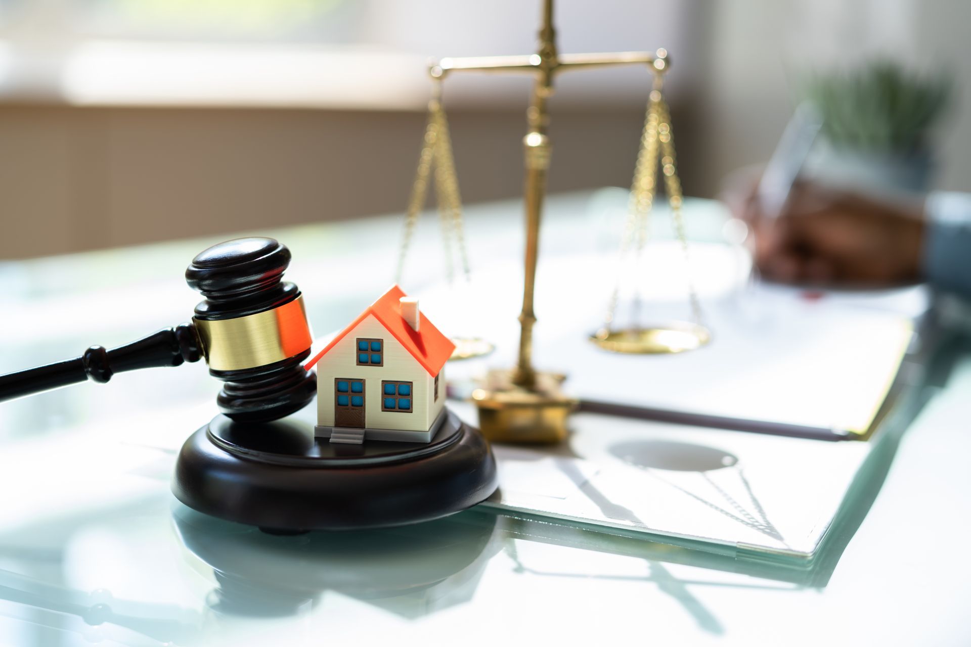 A small model house is sitting on top of a wooden gavel on a table.