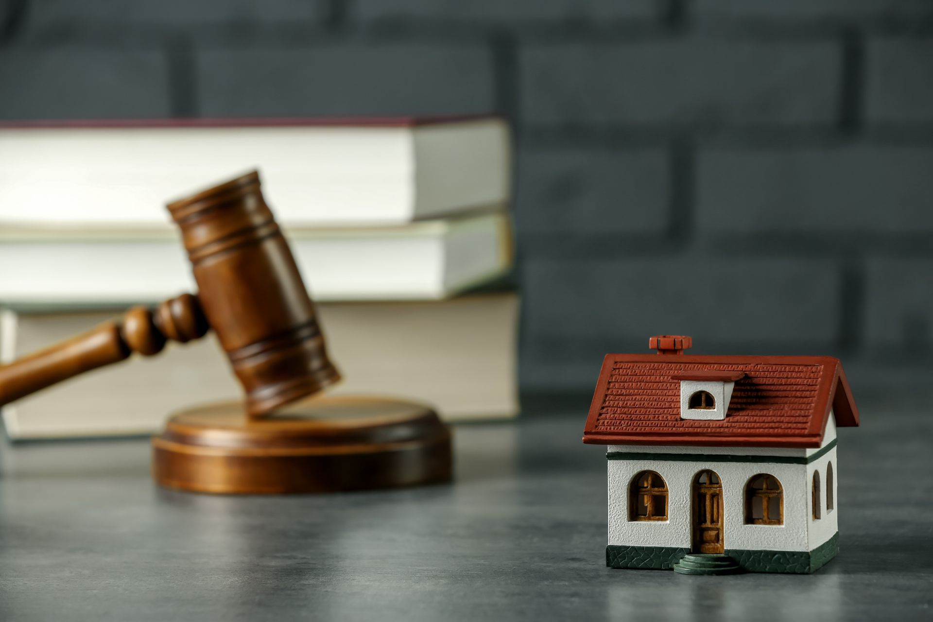 A small model house is sitting next to a wooden gavel on a table.
