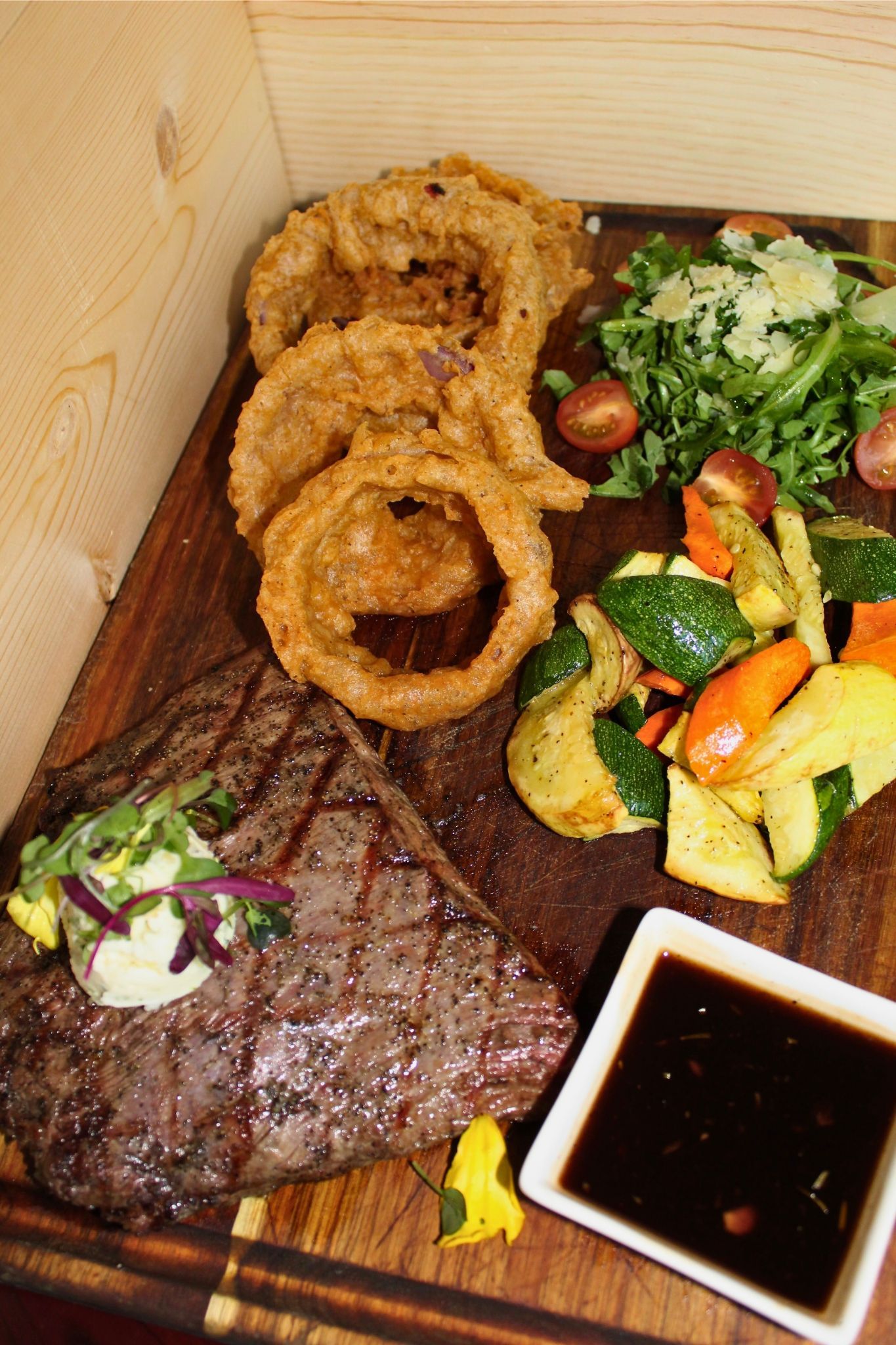 Grilled Flank Steak
Juicy grilled flank steak with compound butter, rosemary balsamic glaze, seasonal veggies, and crispy onion rings.