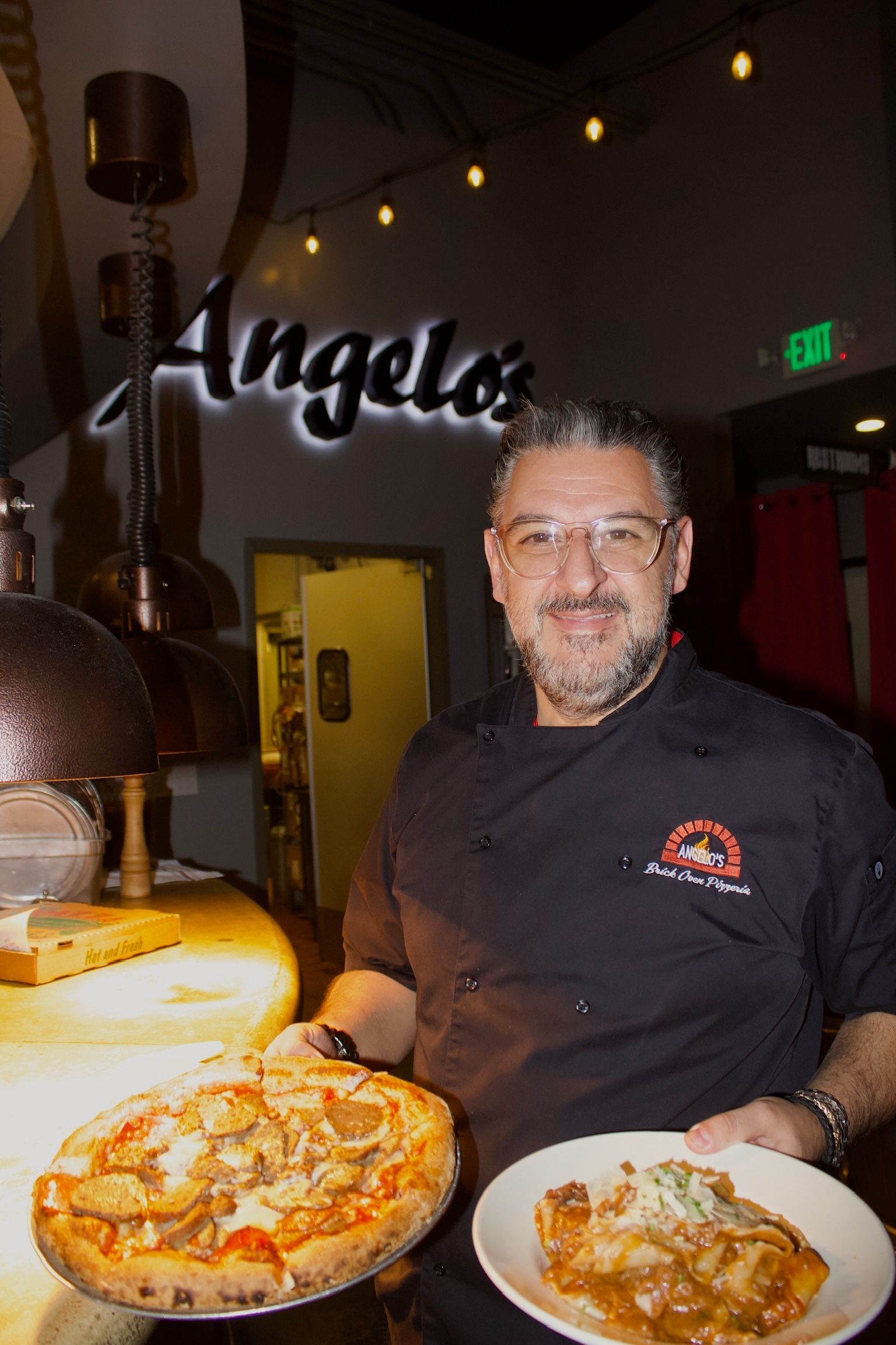 Angelo carrying brick oven pizza to tables in local italian restaurant