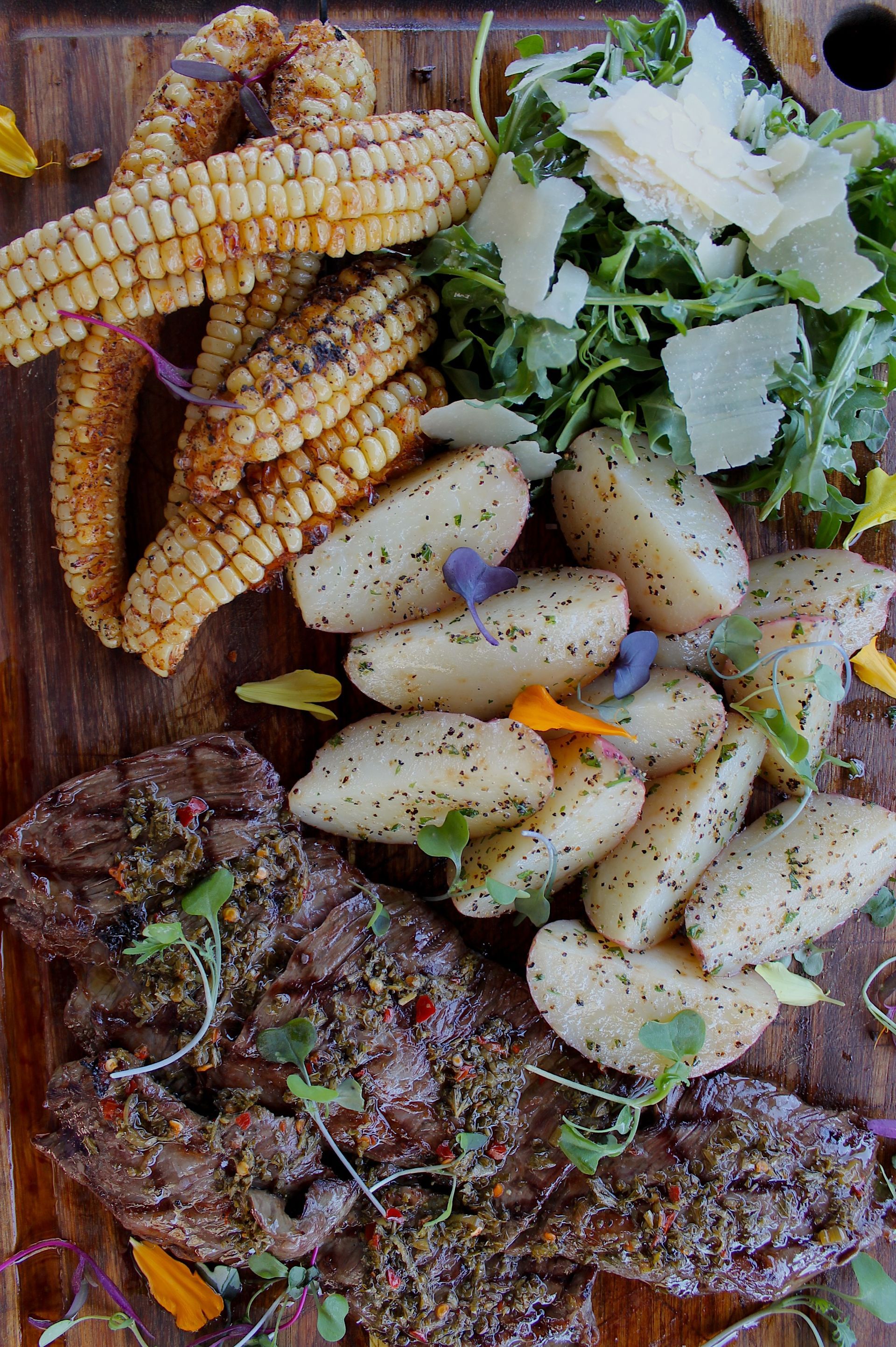 skirt steak, served with roasted + Cajun-seasoned corn ribs and baby red potatoes .