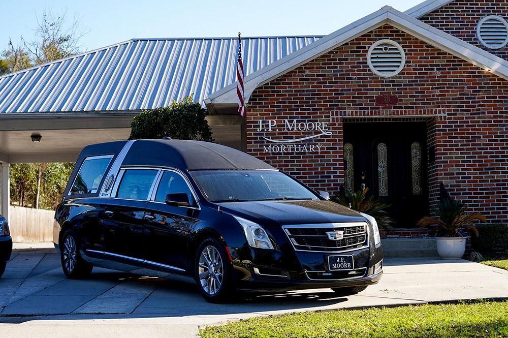 The inside of a church with rows of wooden benches and stained glass windows.