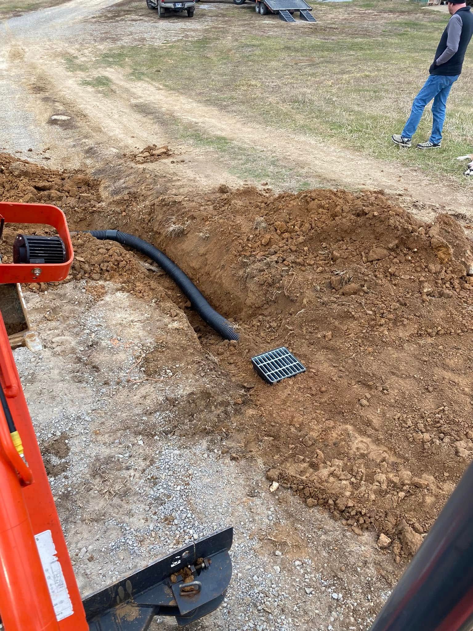 A man is standing in the dirt next to a tractor.