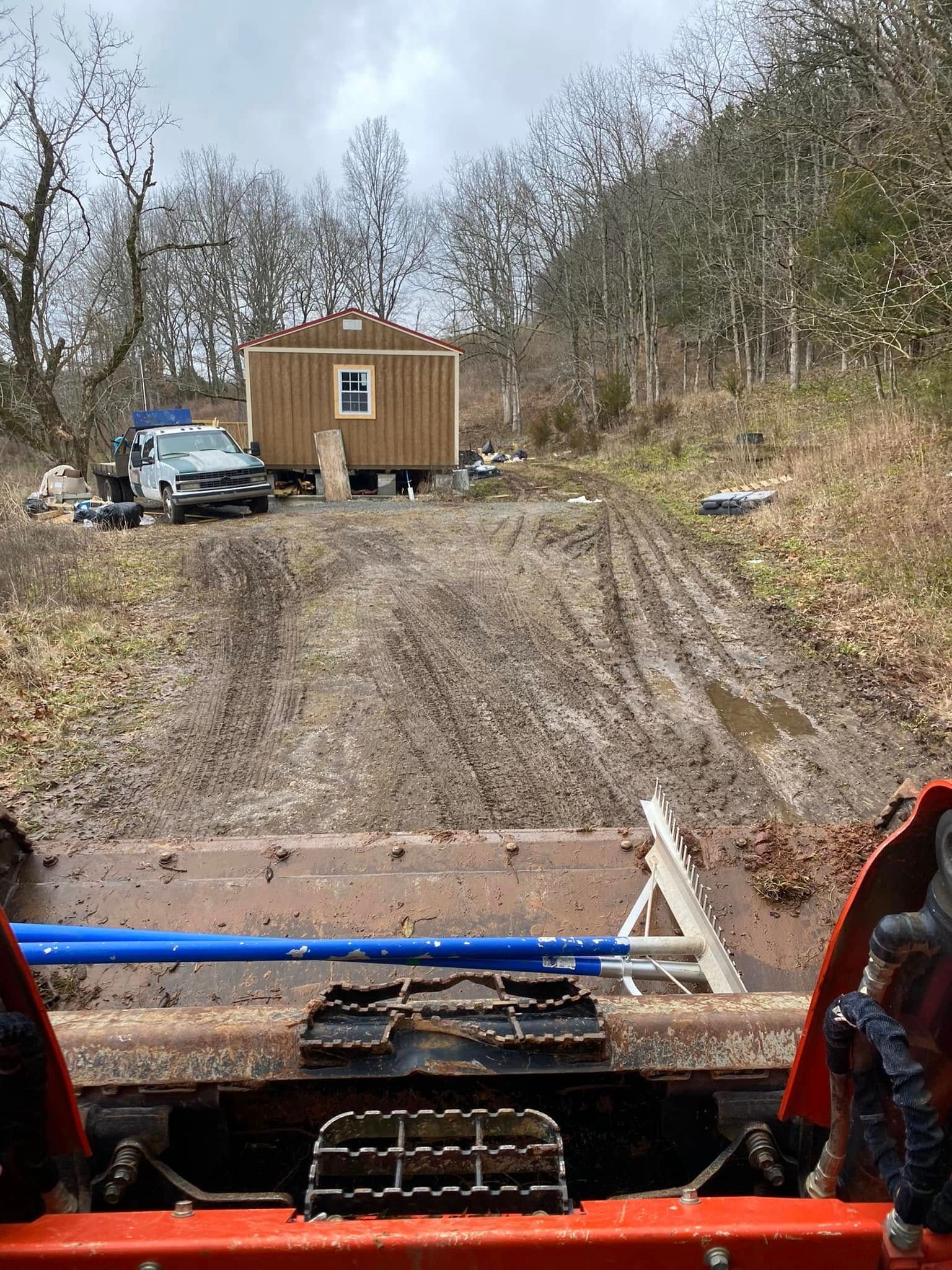 A person is driving a tractor down a muddy road.