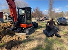 A yellow excavator is scooping dirt out of a large bucket.
