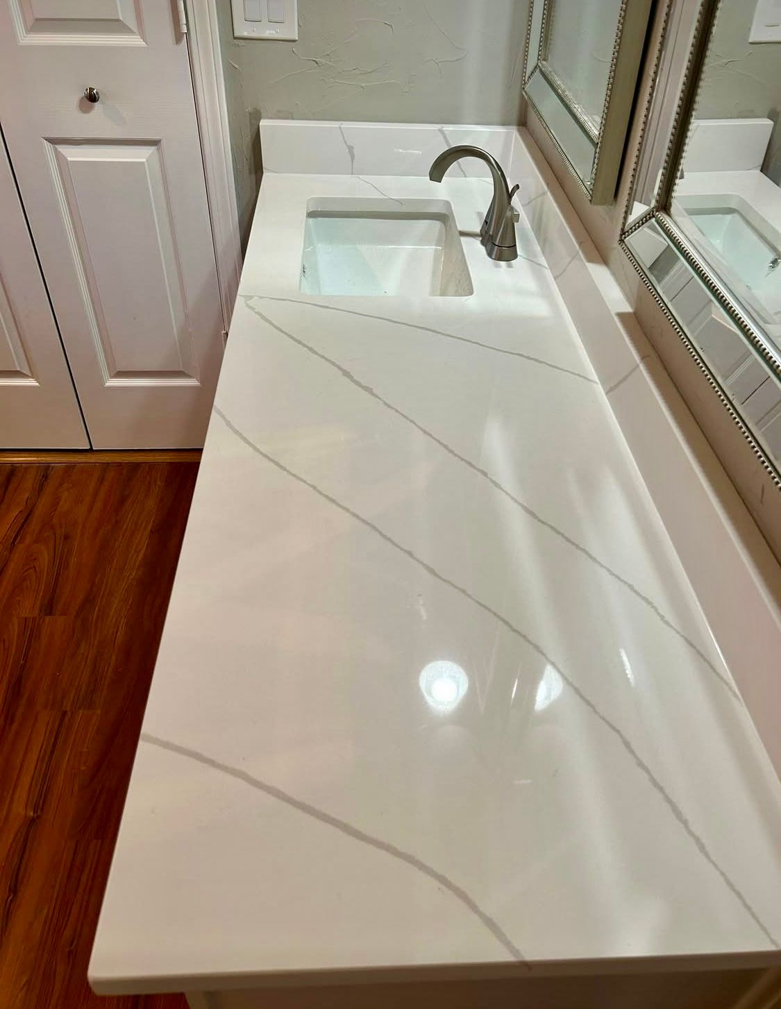 White quartz bathroom countertop with sink and faucet. Diagonal gray veining.