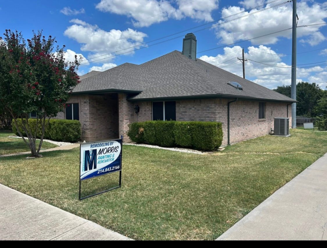 A one-story brick building with a sign in the yard; blue sky with clouds.