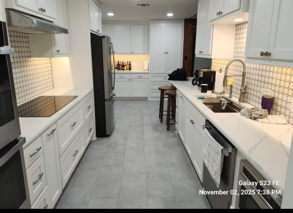White kitchen with appliances, cabinets, and a tile backsplash.