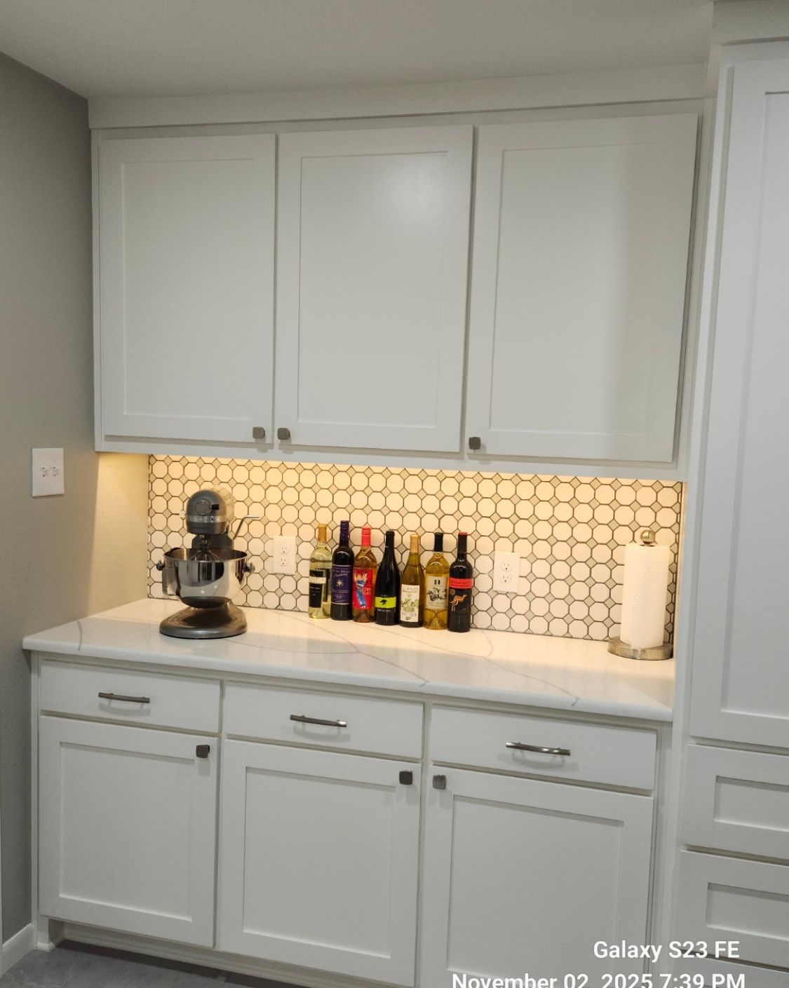 White kitchen cabinets with countertop, backsplash, and appliances.