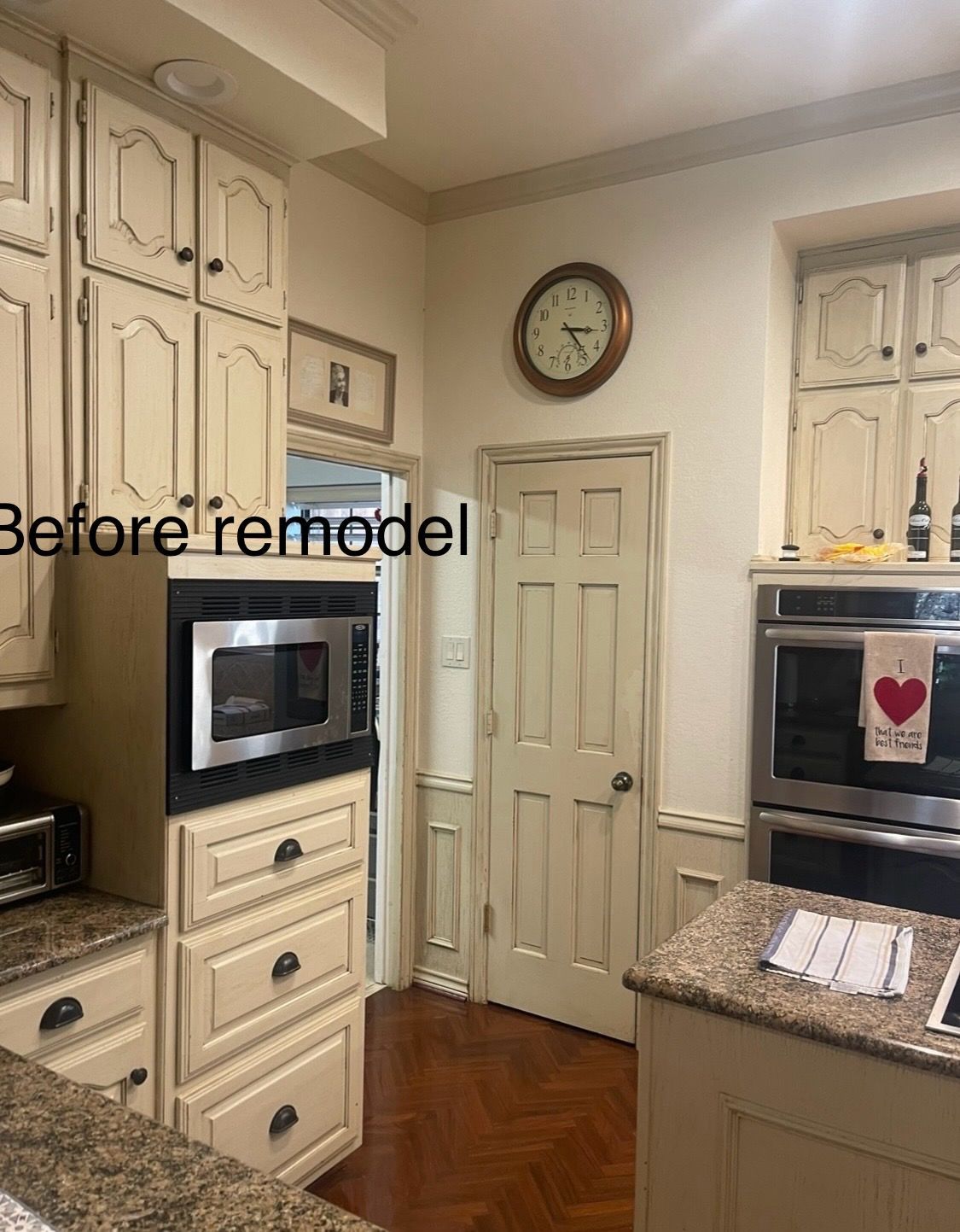 A Kitchen with White Cabinets and A Clock on The Wall.