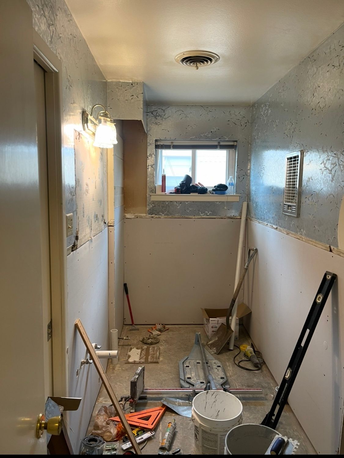 A bathroom is being remodeled with tools and a window.