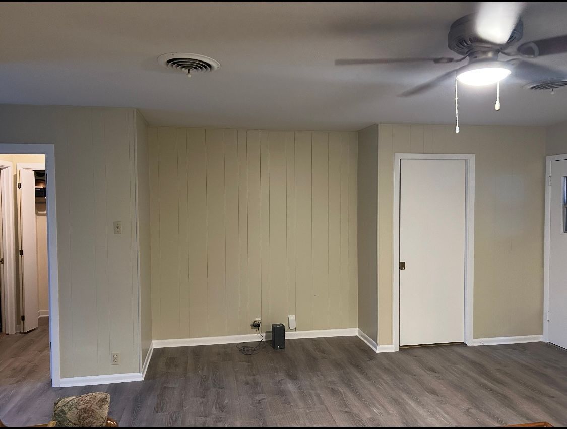 A living room with a ceiling fan and a door.