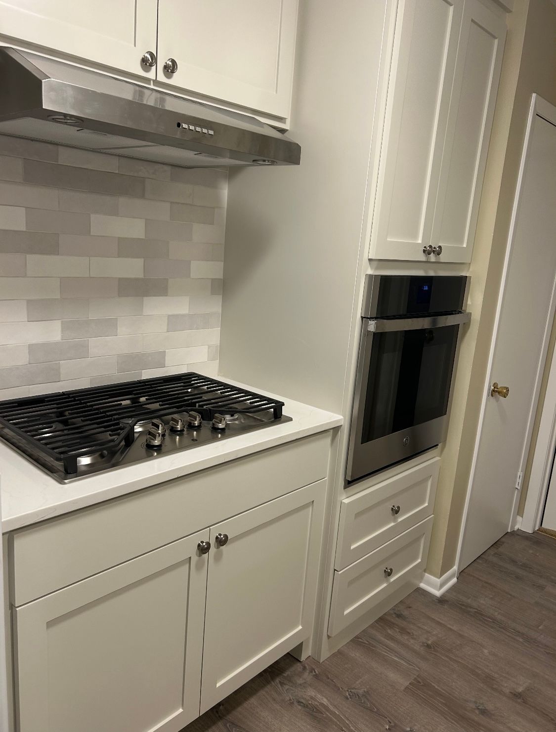A kitchen with white cabinets , a stove top oven , and a hood.