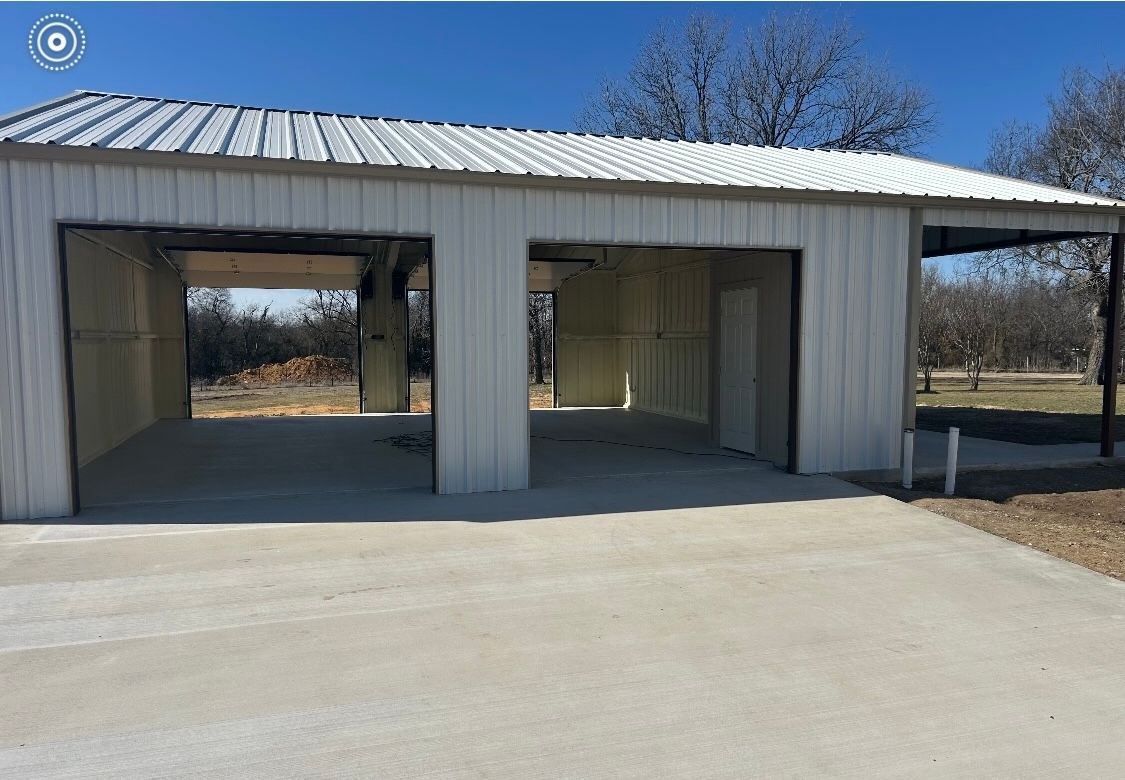 A metal garage with a concrete driveway and a metal roof.