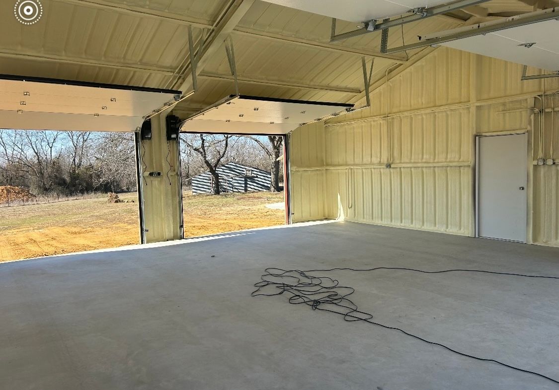 An empty garage with a garage door open and a concrete floor.