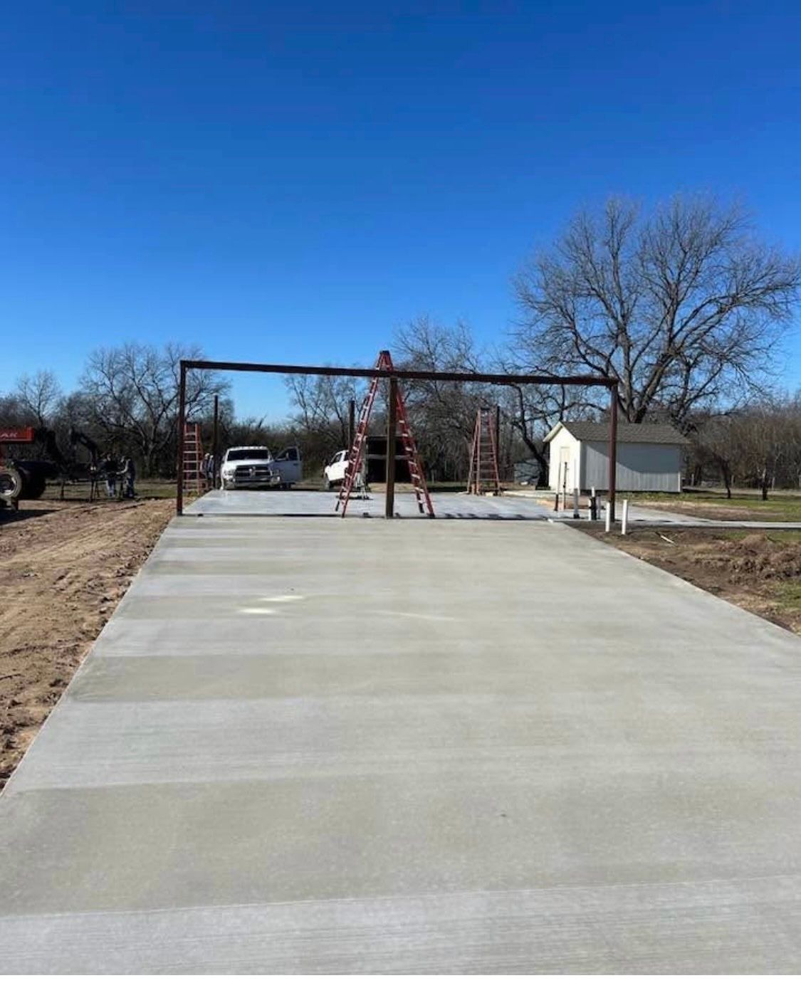 A concrete driveway with a swing set in the background