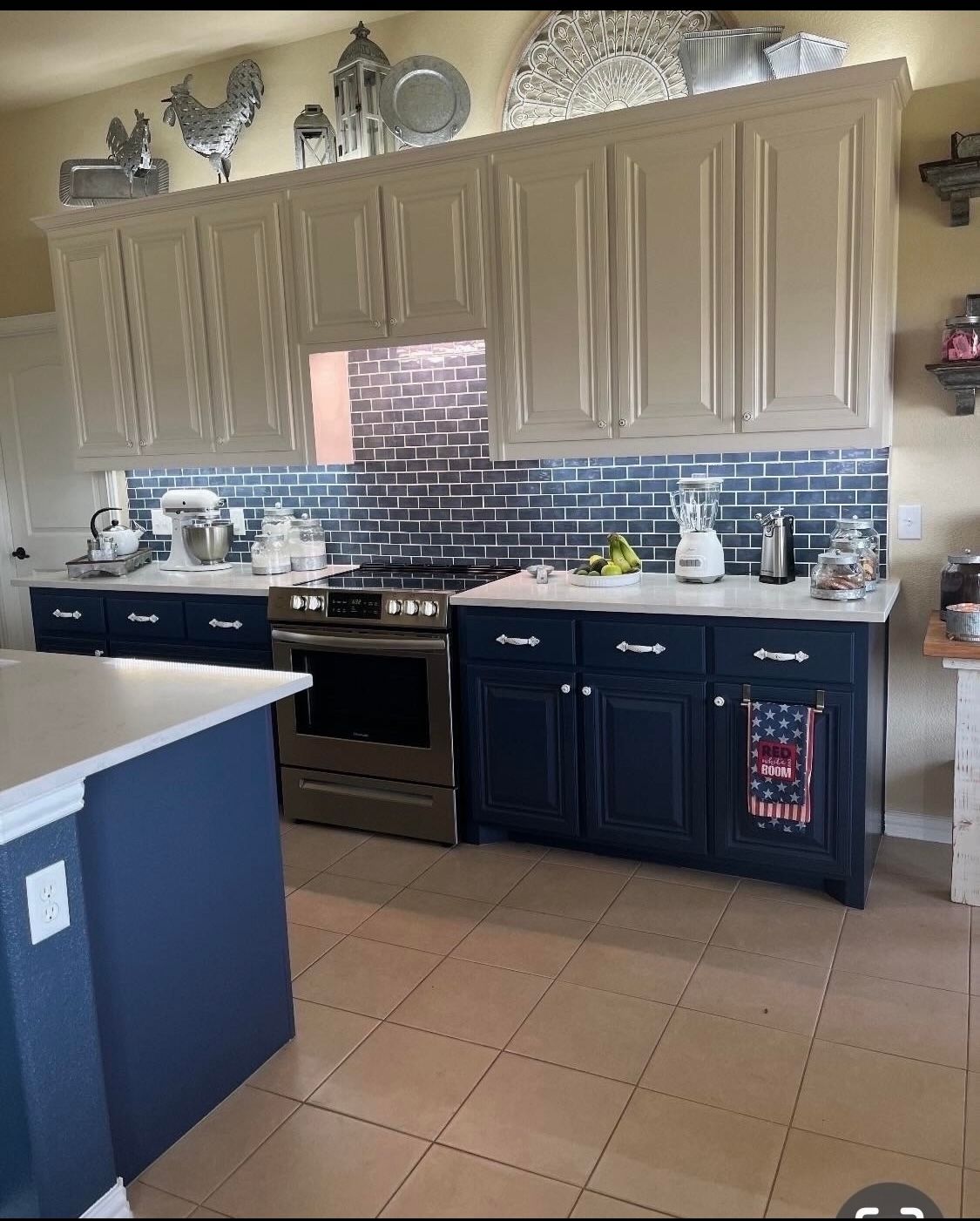 Kitchen with navy and white cabinets, stainless steel appliances, and blue backsplash.