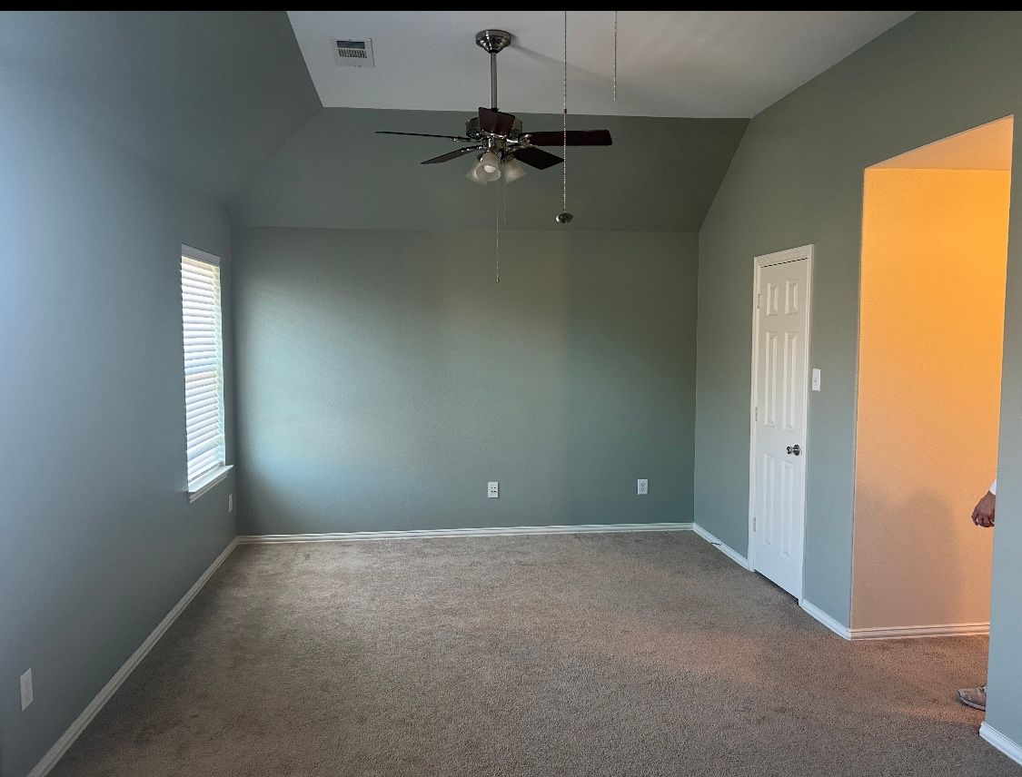 An empty living room with a ceiling fan and a window