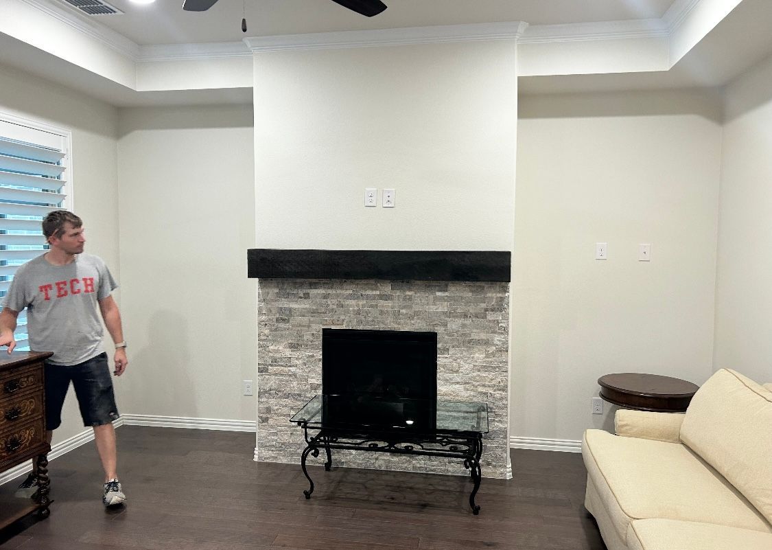 A man is standing in a living room with a fireplace and a couch.