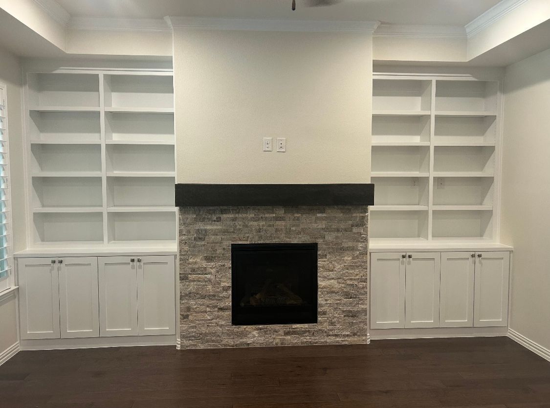An empty living room with a fireplace and shelves