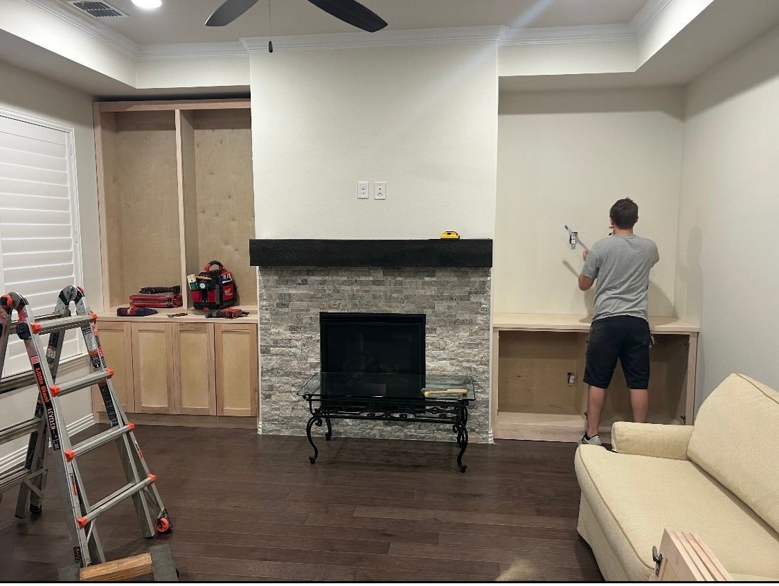A man is working on a fireplace in a living room.