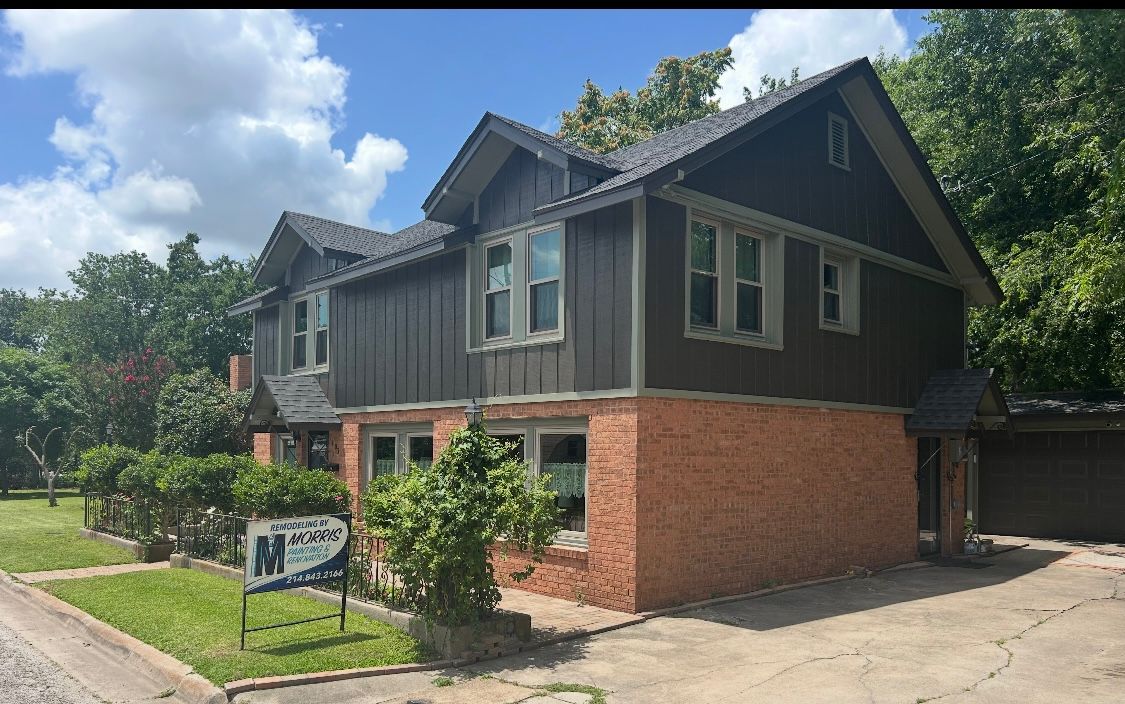 A large brick house with a black roof is for sale.