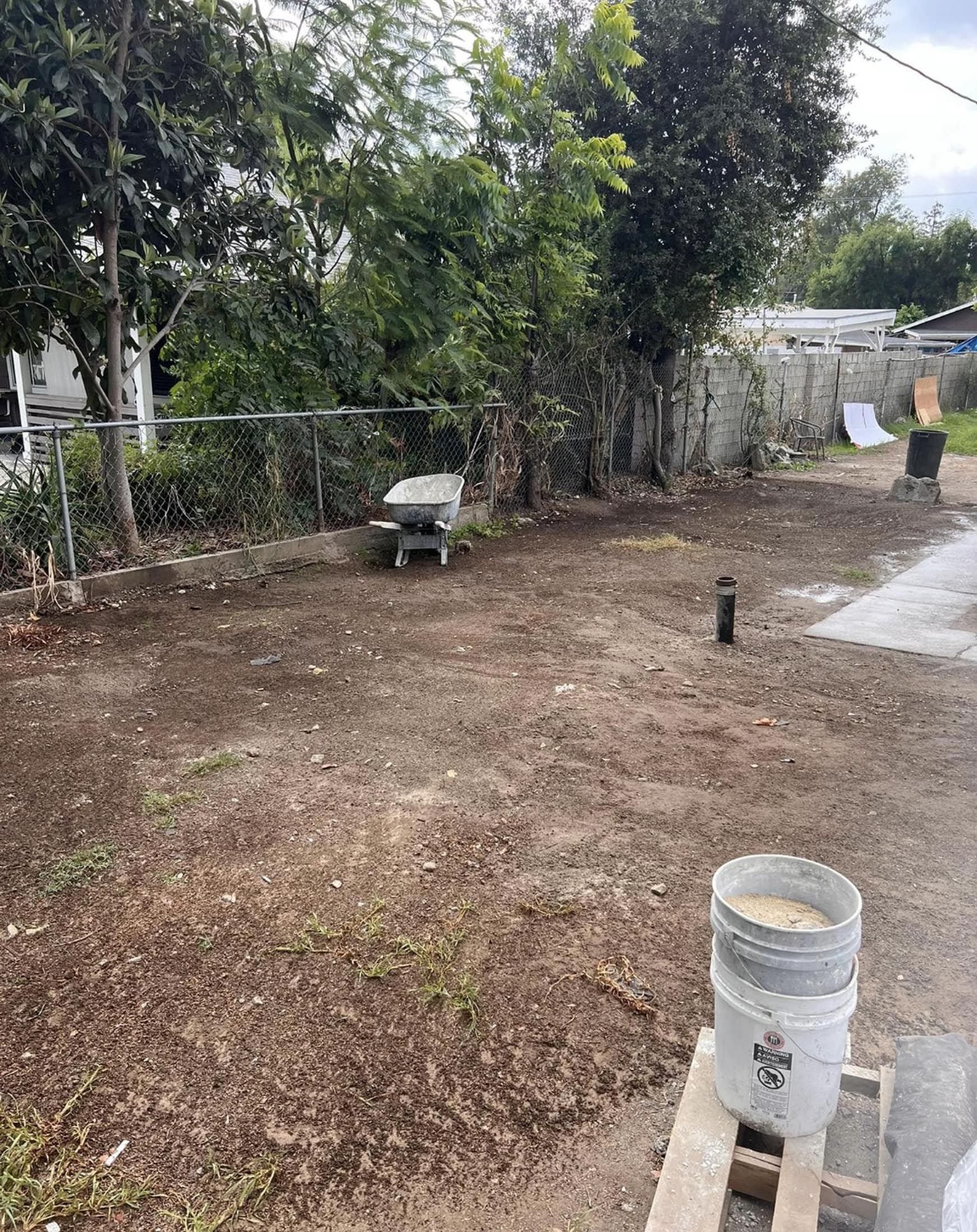 A bucket of dirt is sitting in the middle of a dirt field.