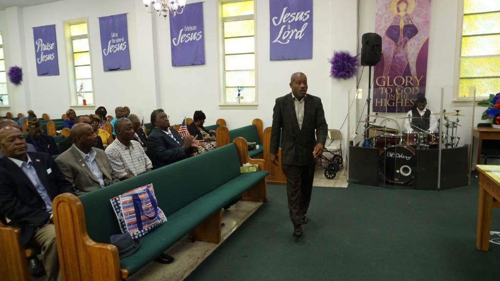 A man is walking through a church with people sitting in the pews.