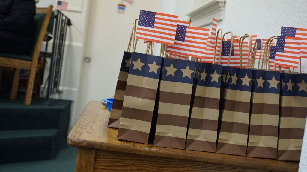 A row of paper bags with american flags on them are sitting on a wooden table.