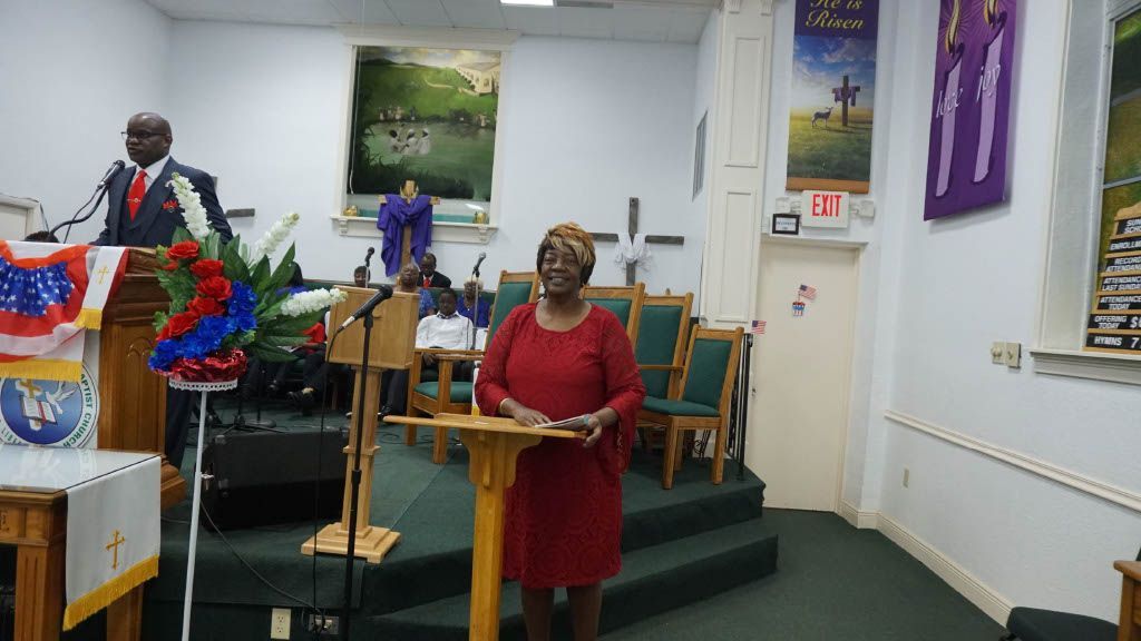 A woman is standing at a podium giving a speech in a church.
