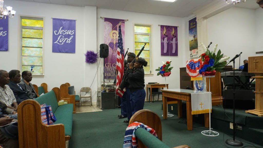 A group of people are sitting in a church with a jesus lord banner on the wall.
