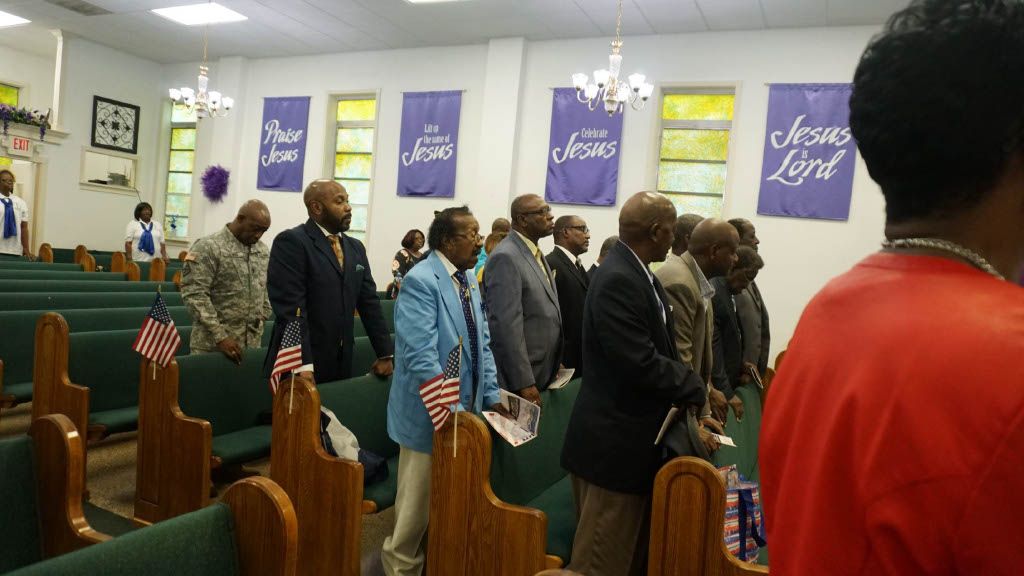 A group of people are standing in a church with purple banners that say jesus is lord