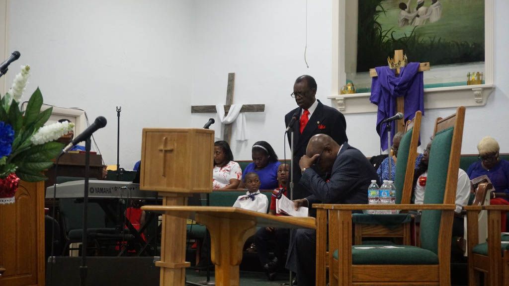 A man is standing at a podium in a church talking to a group of people.