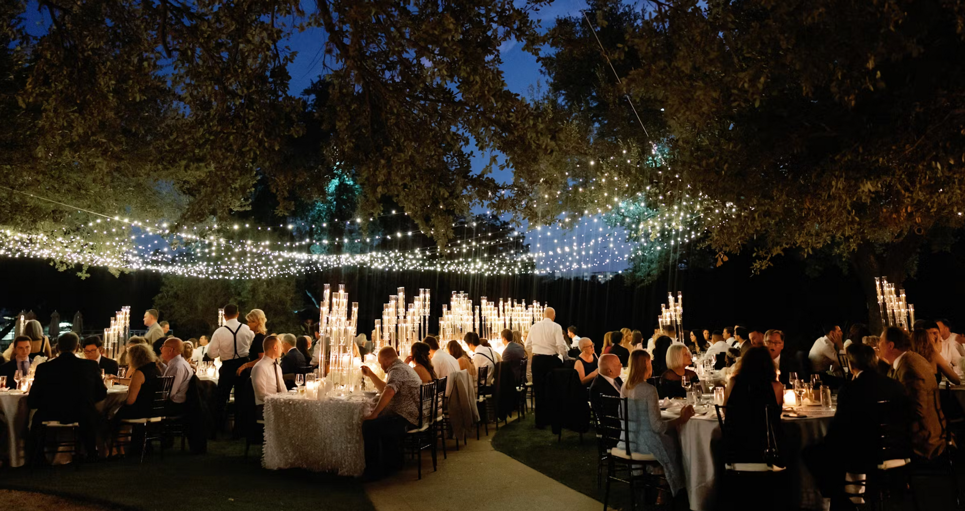 A large group of people are sitting at tables outside at night.