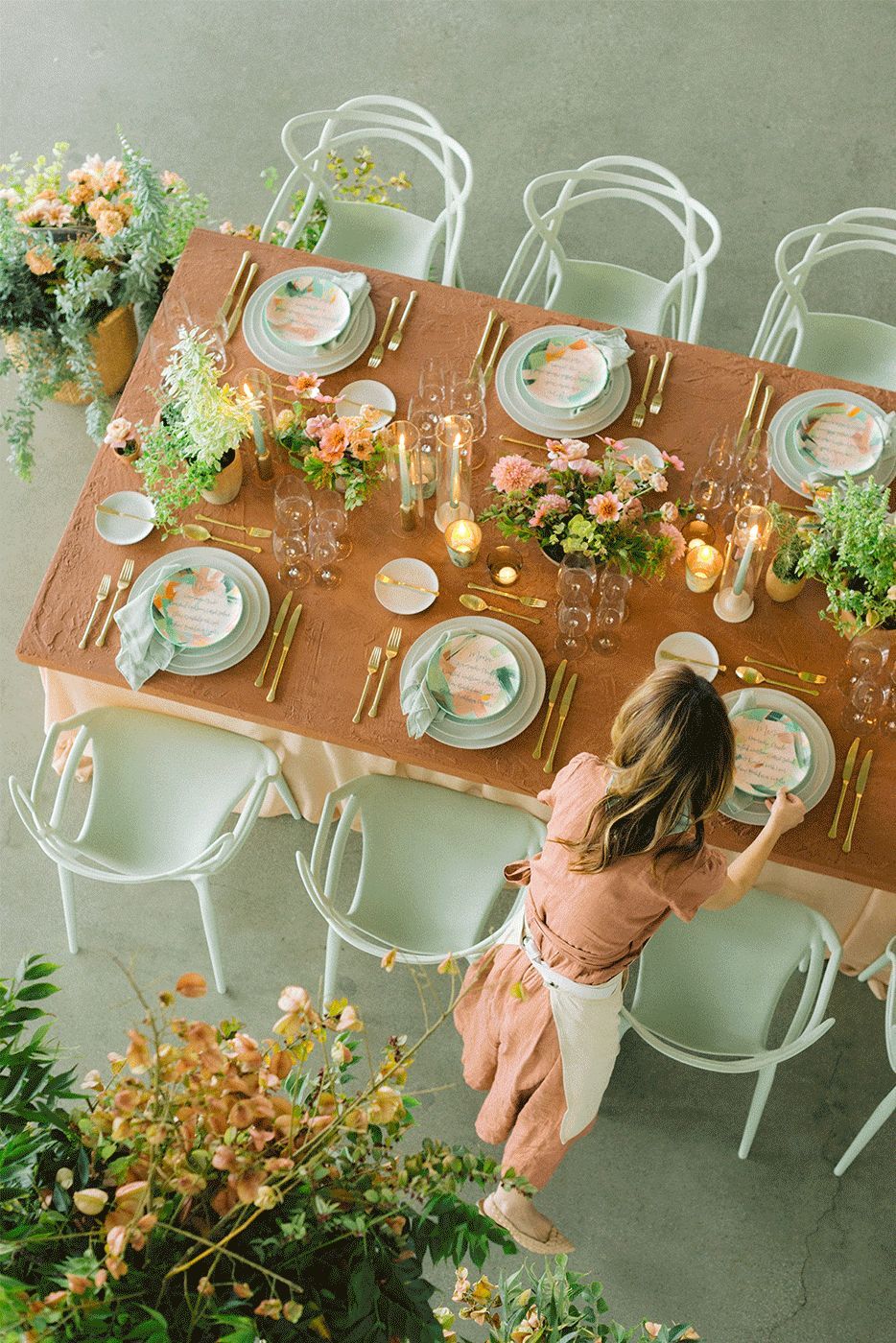 A woman is standing in front of a table set for a wedding reception.