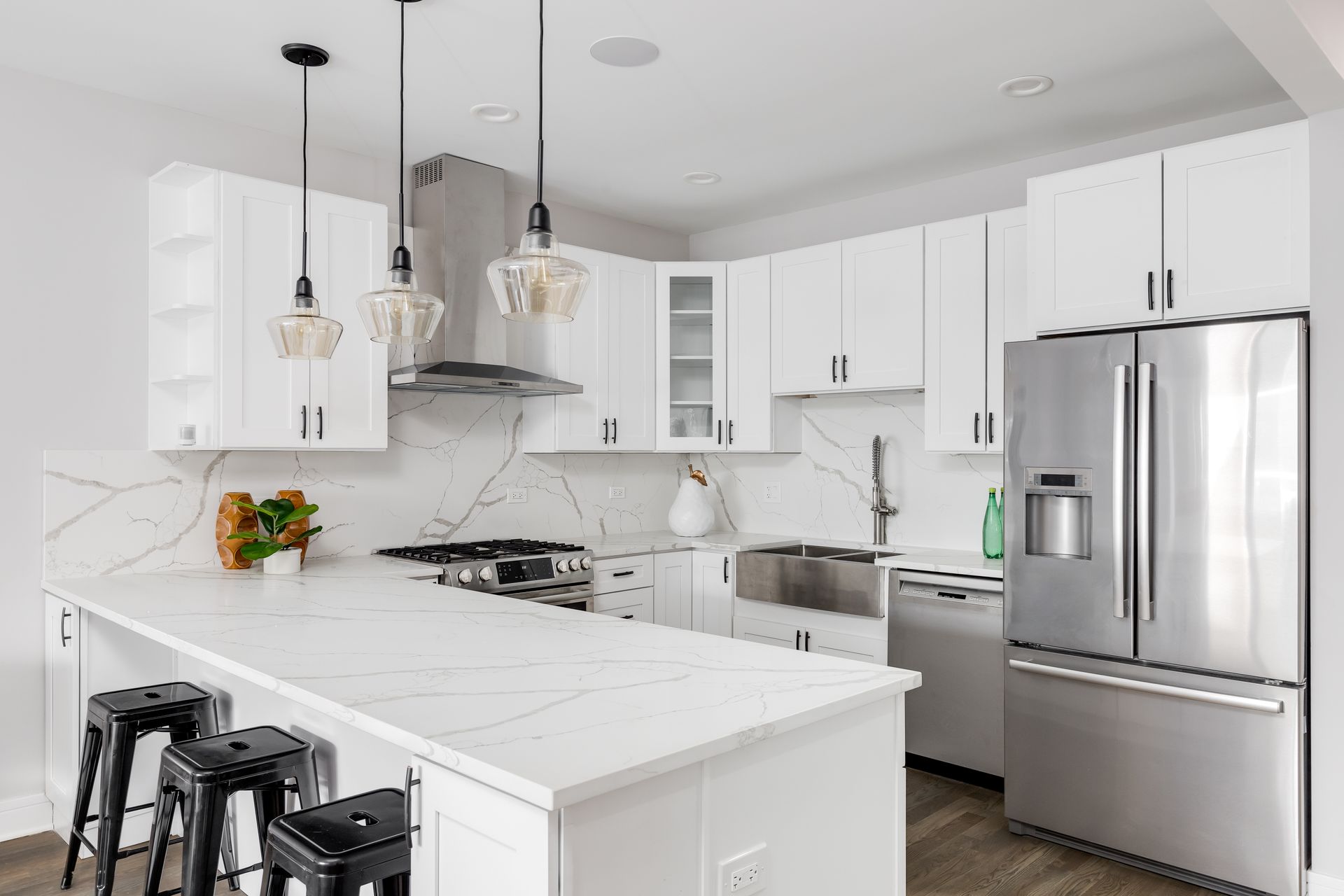 Bright white modern kitchen with island, stainless steel appliances, and pendant lights
